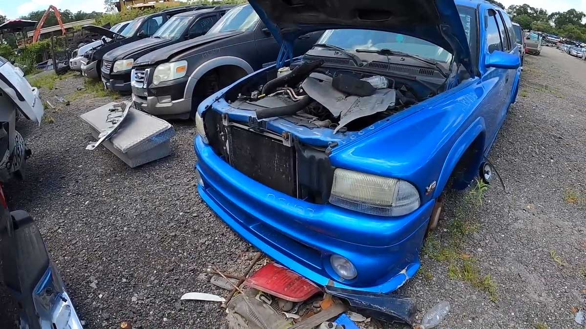 Person searching through rows of salvaged car parts at a junkyard